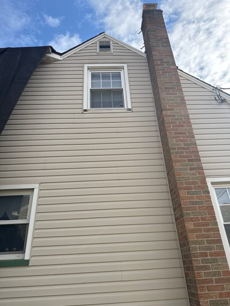Before: faded beige vinyl siding and chimney on the side of a Cape-style home in Garwood NJ